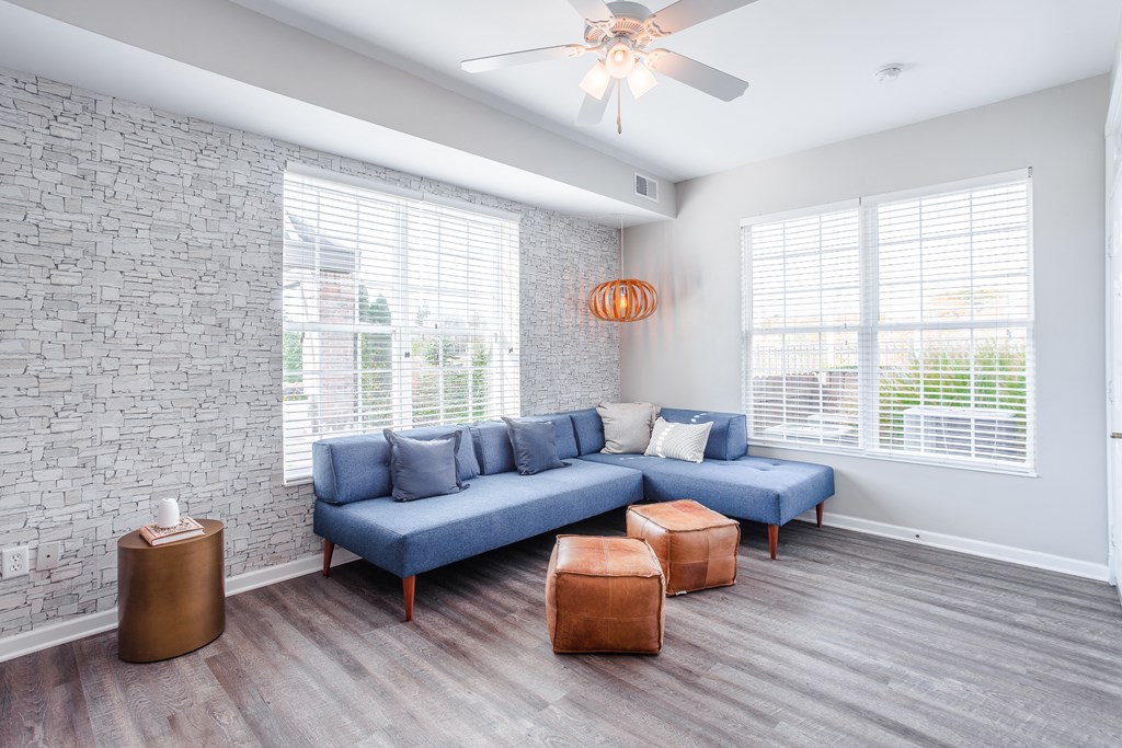 A living room with a blue couch and a ceiling fan.