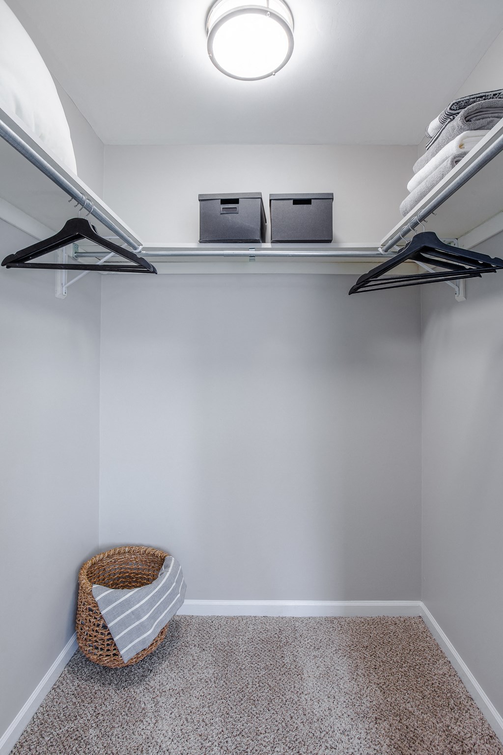 A small closet with a laptop and two containers on a shelf.