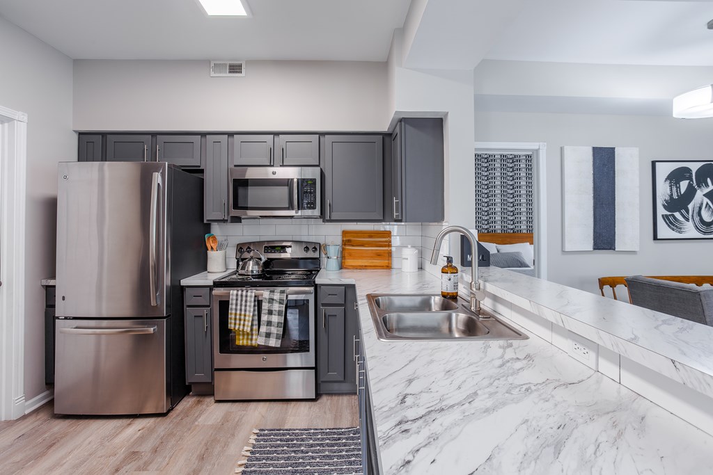 A modern kitchen with stainless steel appliances and a marble countertop.