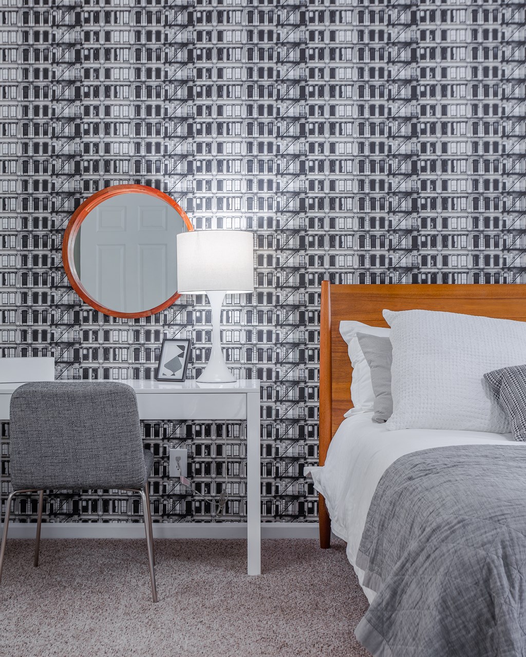 A bedroom with a bed, chair, and a mirror.