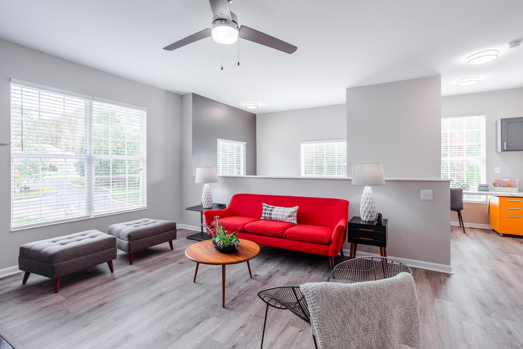 A living room with a red couch, a coffee table, and a ceiling fan.