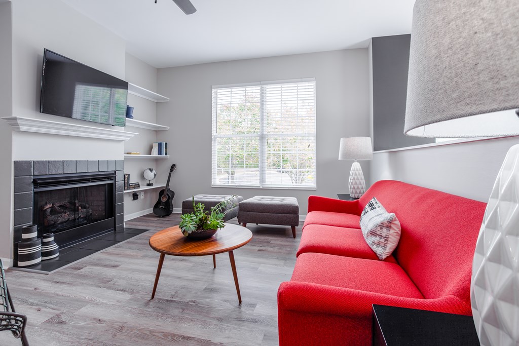 A living room with a red couch and a fireplace.