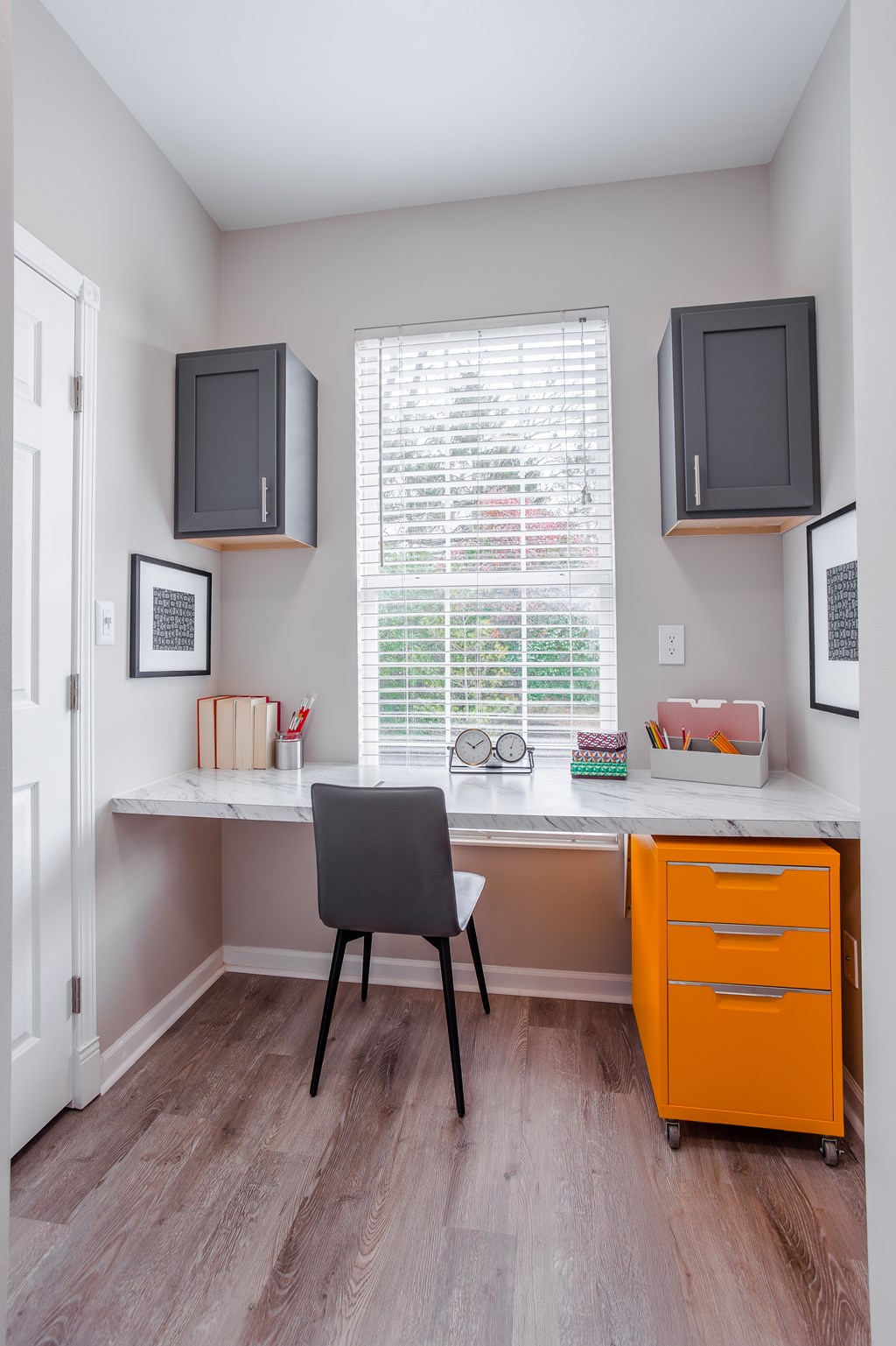 A small home office with a desk, chair, and two mounted TVs.