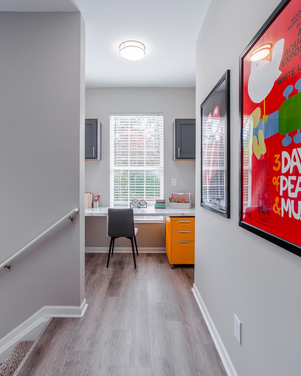 A room with a desk and a chair in front of a window with blinds.