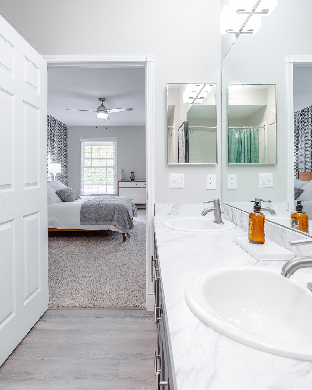 A white bathroom with a bedroom entrance.