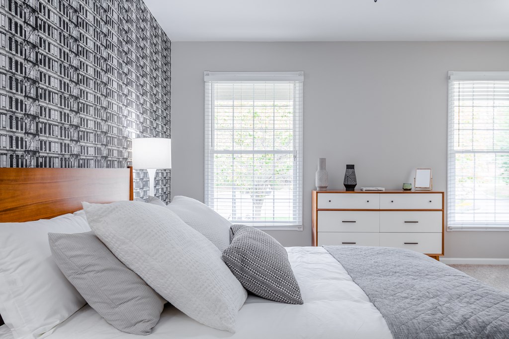 A bedroom with a bed, nightstand, and a wallpapered wall.
