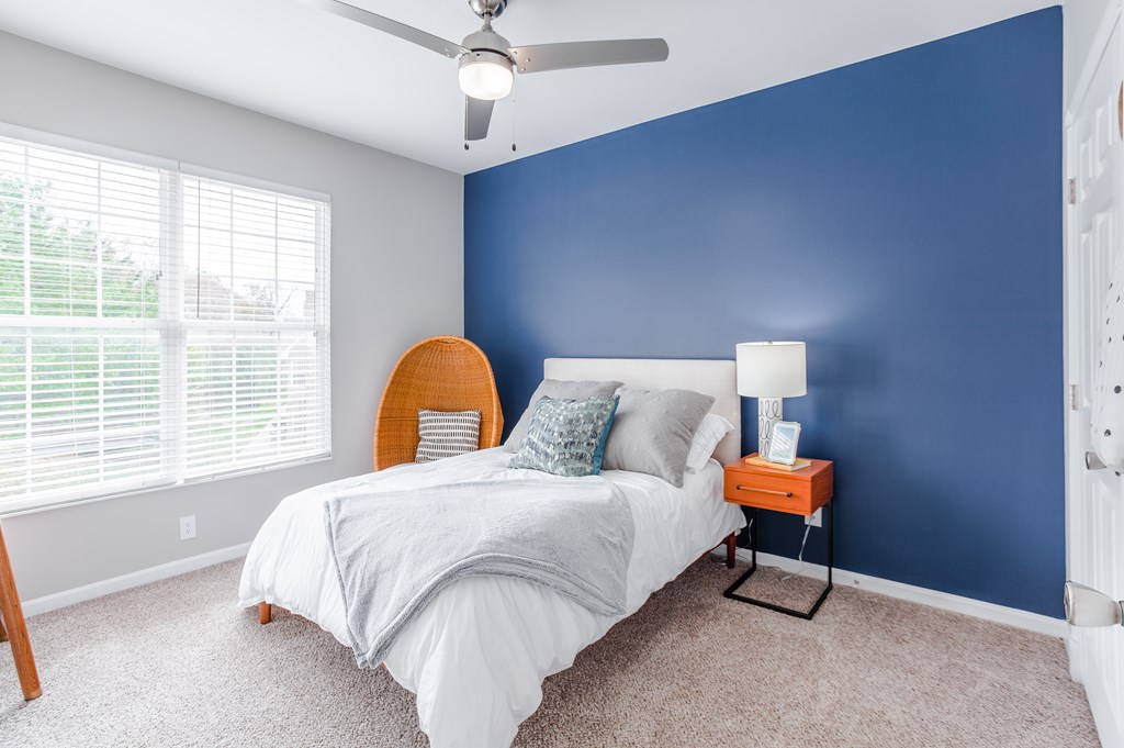 A bedroom with a bed, a ceiling fan, and a window with blinds.