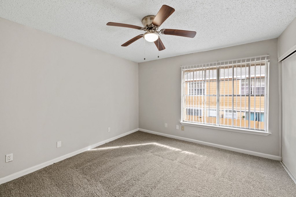 A room with a ceiling fan and a window with blinds.