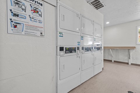 a white kitchen with a row of white refrigerators in it