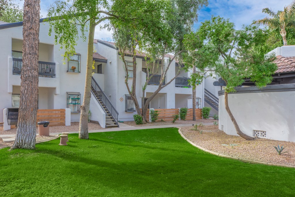 a grassy area with trees and buildings in the background