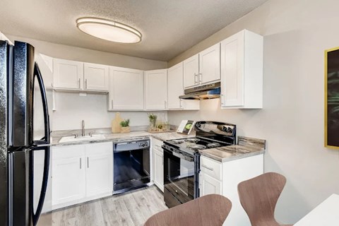 A kitchen with white cabinets and a black fridge.