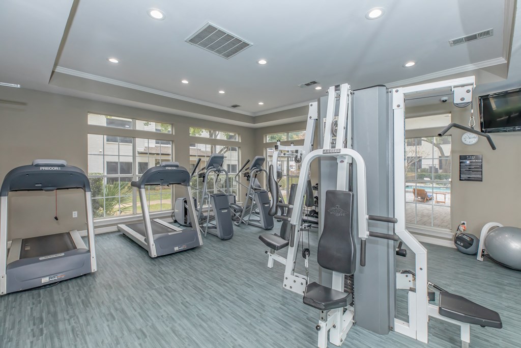 a gym with cardio equipment and a flat screen tv