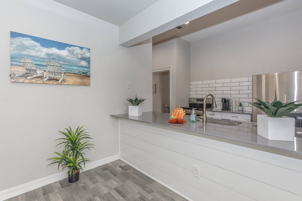a kitchen with white cabinets and a painting of two chairs