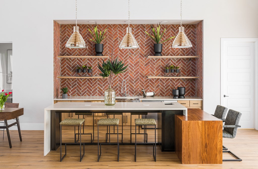 a kitchen with a large island with stools and pendant lights