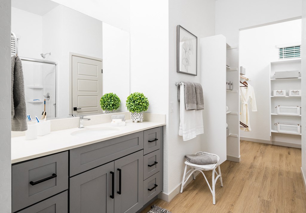 a bathroom with gray cabinets and a white countertop with two green plants on top of it