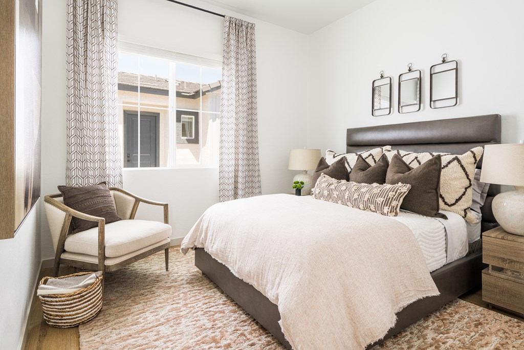 a bedroom with a large bed and a chair in front of a window