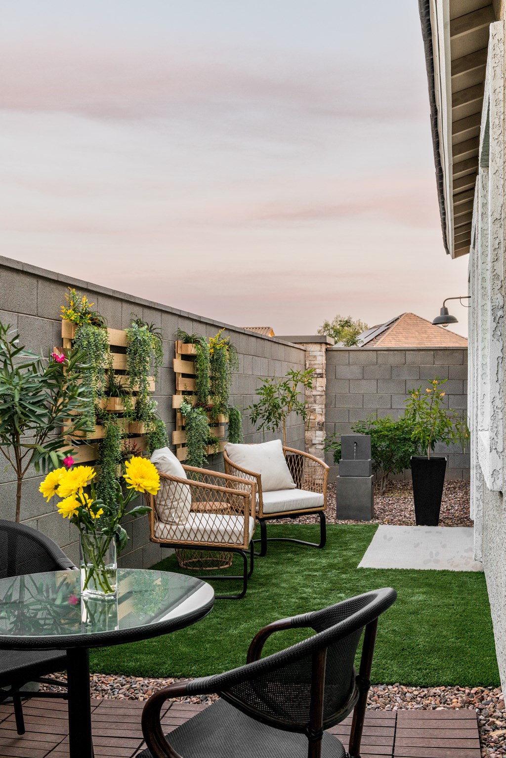 a patio with chairs and a table with a vase of flowers on it