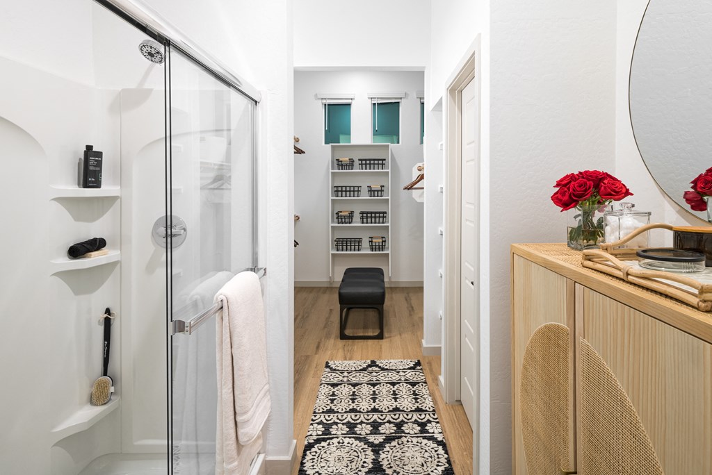 a bathroom with a glass shower stall and a black and white rug