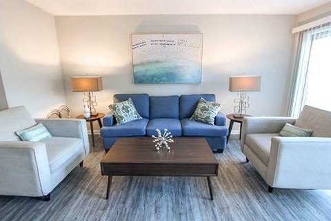 A living room with a blue couch and two white chairs.