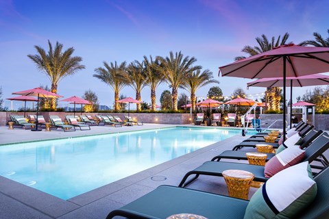 A pool surrounded by palm trees and lounge chairs.