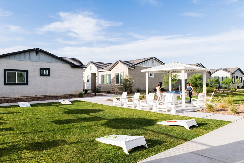 a group of small houses with white benches and chairs on a lawn