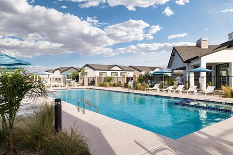 a swimming pool with chairs and umbrellas at the resort on a sunny day