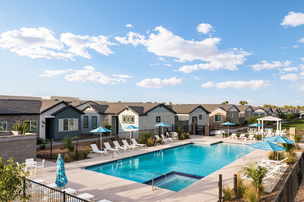 a swimming pool with chairs and umbrellas in front of a row of houses