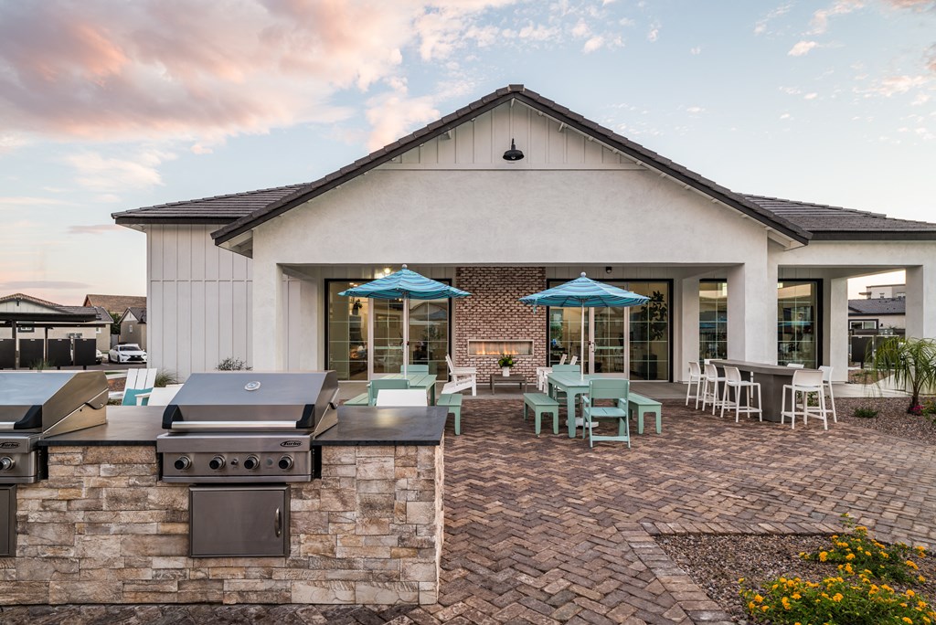 a patio with a grill and tables with umbrellas in front of a building