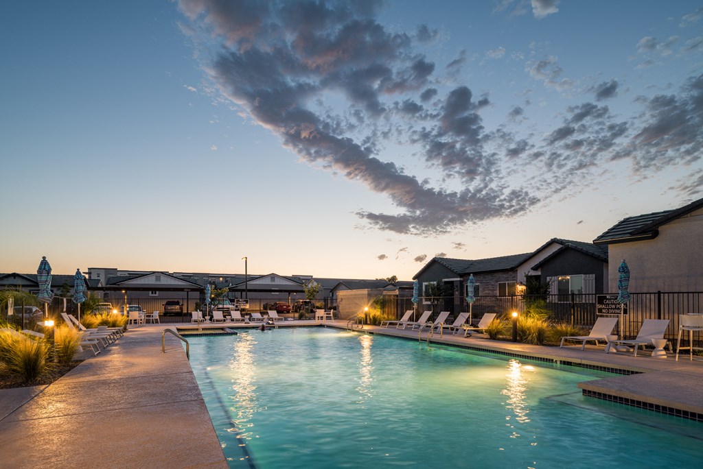 a swimming pool at dusk with chairs around it