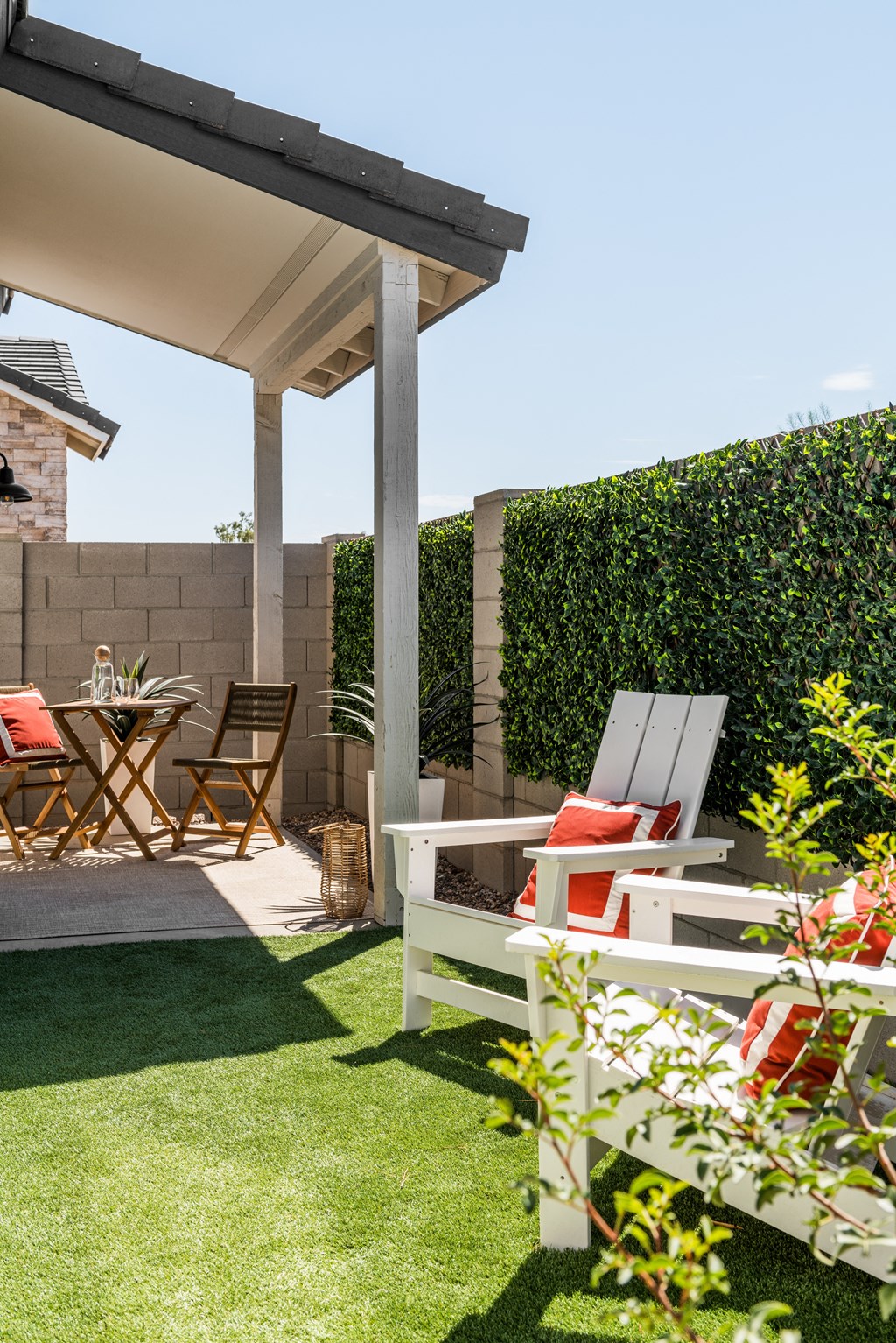 a patio with chairs and a table and a privacy hedge
