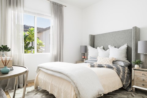 A bedroom with a large bed and a round table with a vase on it.