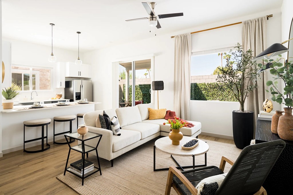 A modern living room with a white sofa, a coffee table, and a ceiling fan.