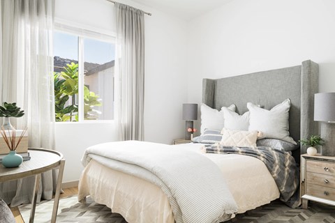 A bedroom with a large bed and a round table with a vase on it.