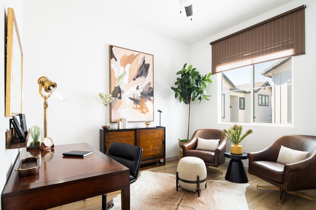 a living room with a desk and chairs and a large window