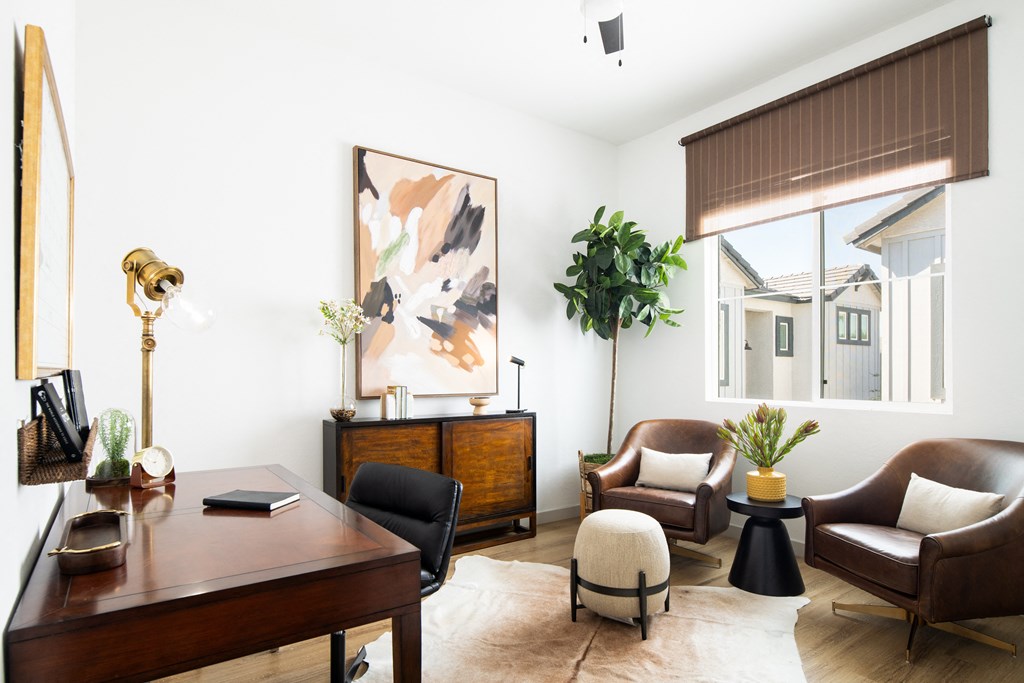 a living room with a desk and chairs and a large window