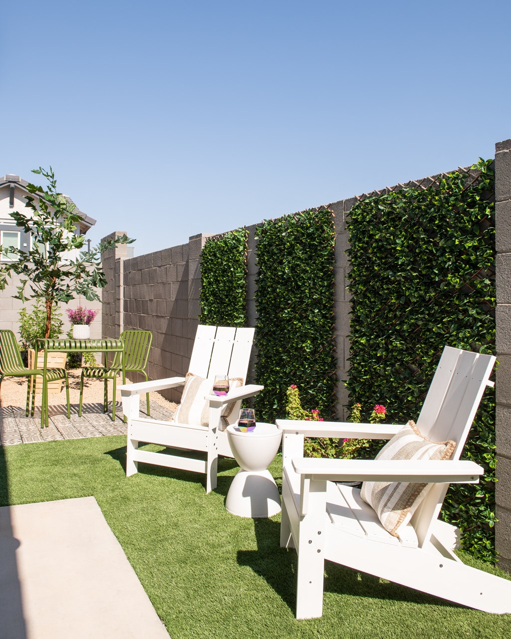 a backyard patio with two chairs and a toilet and a privacy hedge