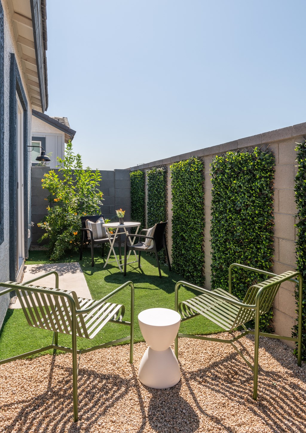 a small backyard with a table and chairs and a privacy hedge
