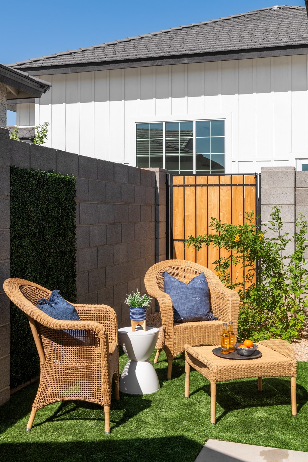 a backyard patio with two rattan chairs and a coffee table