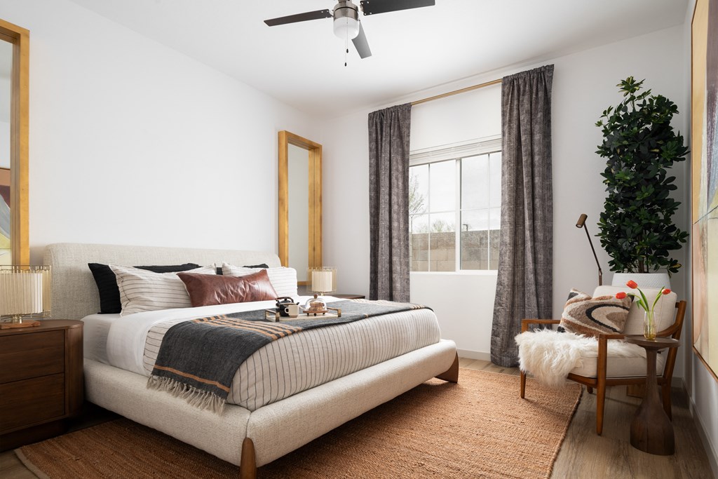 a bedroom with a bed and a plant and a ceiling fan