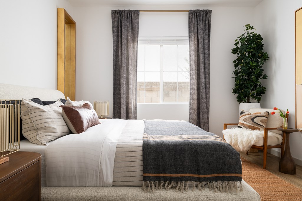 a bedroom with a bed and a plant and a window