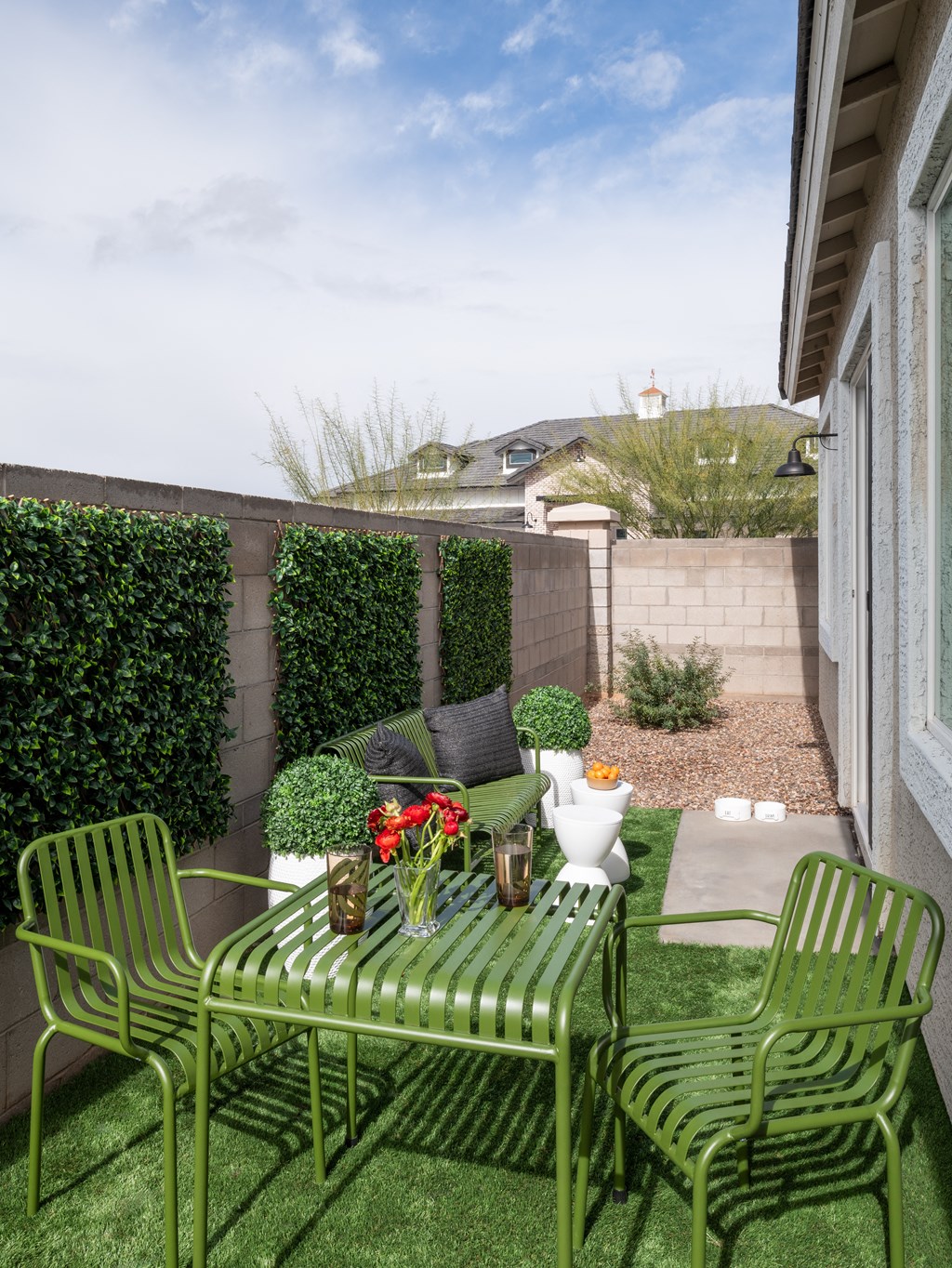 a small patio with green chairs and a table with flowers on it