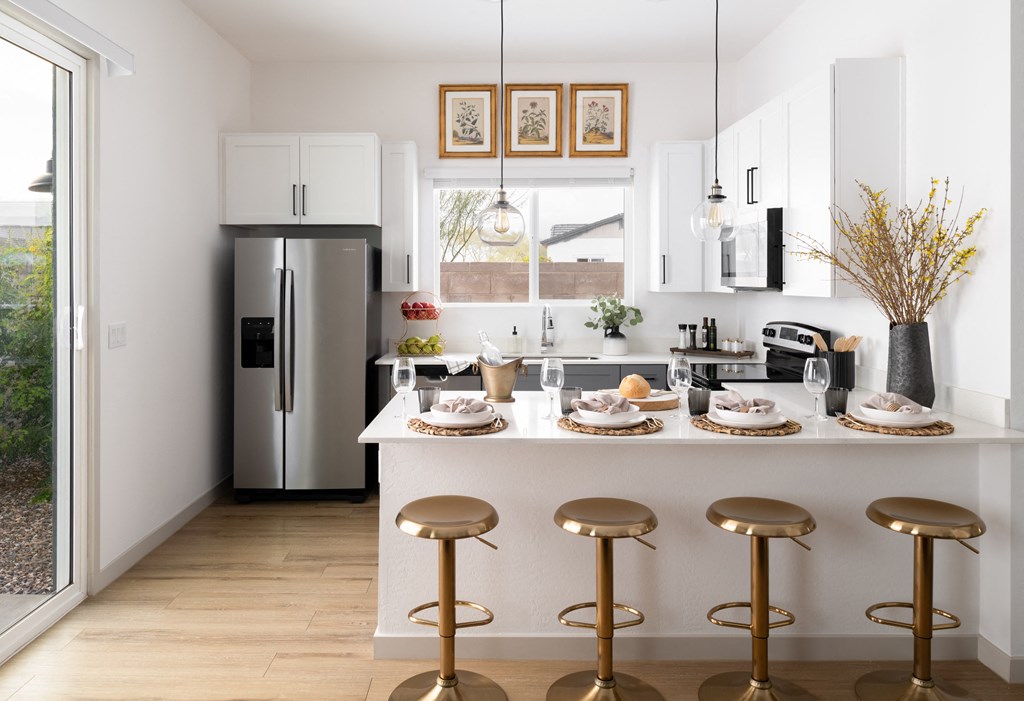 a kitchen with a island with stools and a stainless steel refrigerator