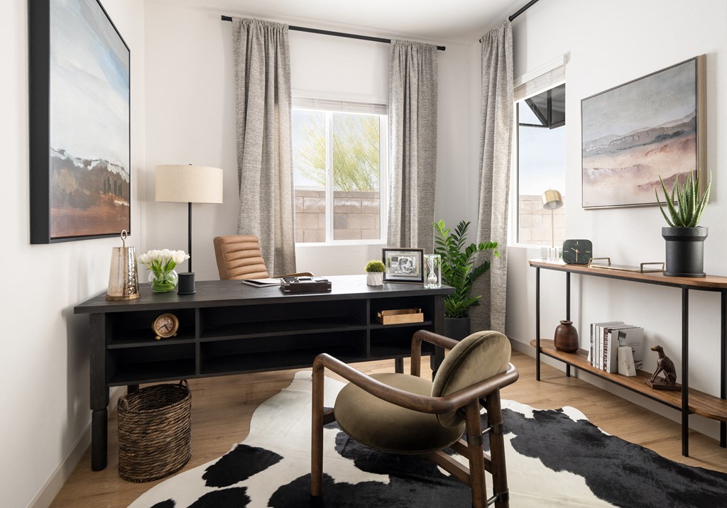 a living room with a desk and a chair in front of a window
