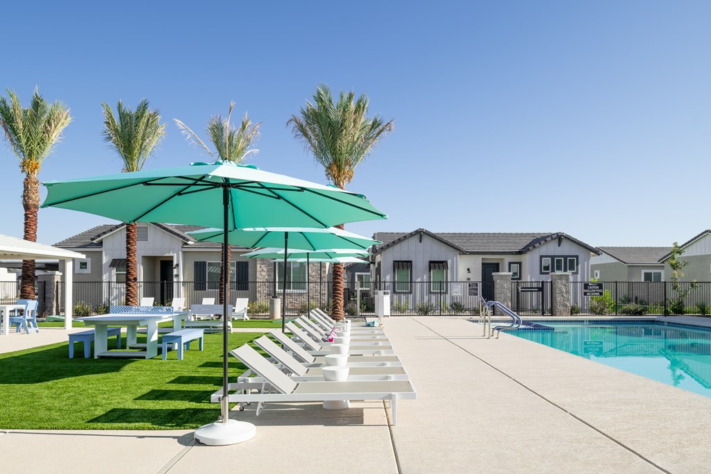 A poolside area with sun loungers and a green umbrella.