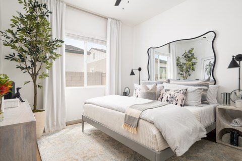 A bedroom with a large bed and a mirror on the wall.
