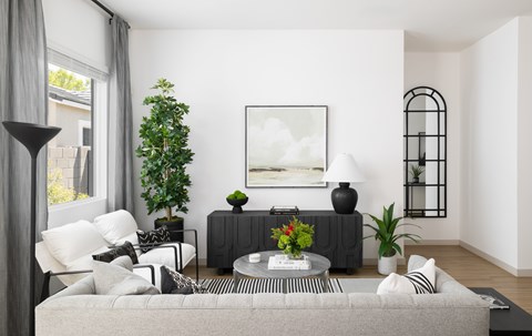 A living room with a grey couch, a coffee table, and a painting on the wall.