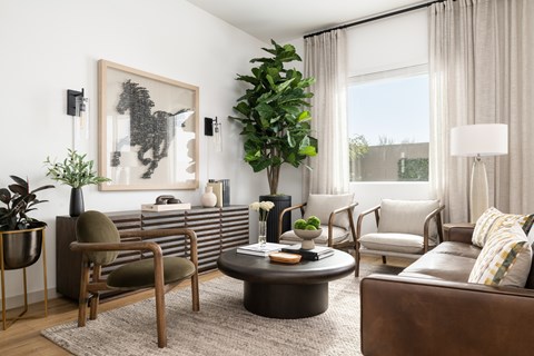 A living room with a brown leather couch, a coffee table, and a large painting on the wall.