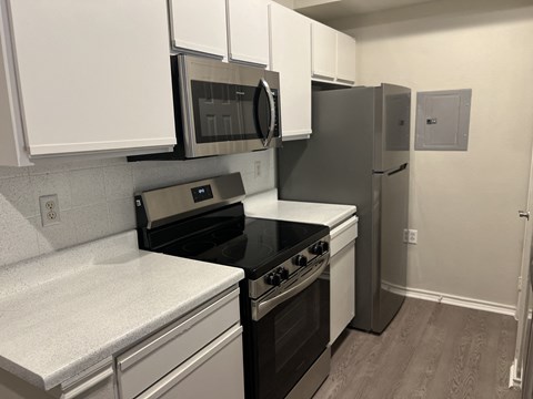 a kitchen with white cabinets and black appliances and a refrigerator