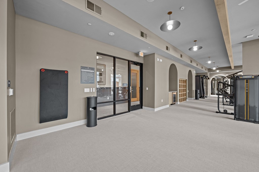 A gym with a variety of equipment including treadmills, weights, and a yoga mat.