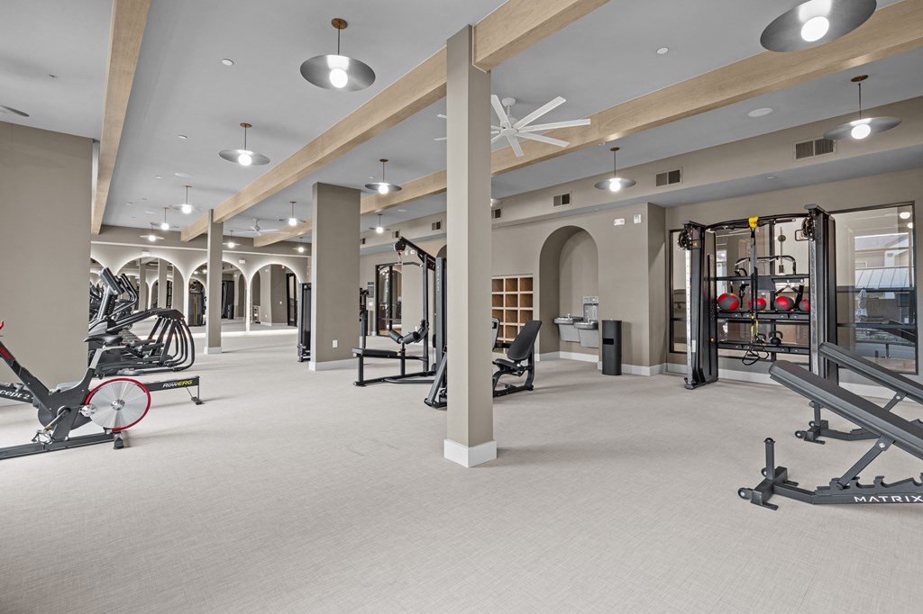 A gym with a variety of equipment including a rowing machine, a leg press machine, and a weight bench.
